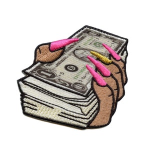 Peut inclure: Une pile de billets de banque tenue par des doigts avec du vernis à ongles rose et or.