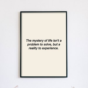 以下が含まれることがあります： 白い背景に黒い文字で「人生の神秘は解決すべき問題ではなく、経験すべき現実である。」と書かれた額装されたプリント