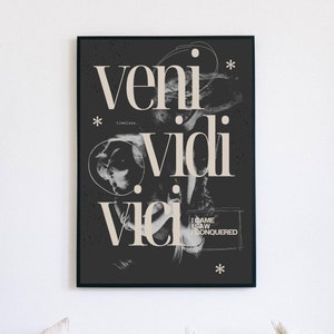 May include: Black and white poster with the Latin phrase "veni vidi vici" in large, stylized font. The text "I came I saw I conquered" is written in smaller font below the main text. The poster has a black background and white text.