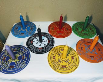 May include: Seven circular wooden candle holders with intricate designs and candles in various colors, including blue, red, black, purple, and yellow.