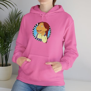 May include: A bright pink hooded sweatshirt featuring a cartoon character in a circular design on the front. The character has brown hair and is wearing a yellow shirt with purple suspenders. The sweatshirt has a kangaroo pocket and a drawstring hood.