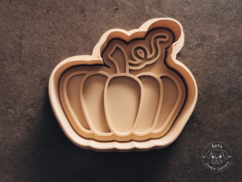 Puede incluir: Un cortador de galletas de calabaza de pl&aacute;stico beige con un tallo y nervaduras detalladas.