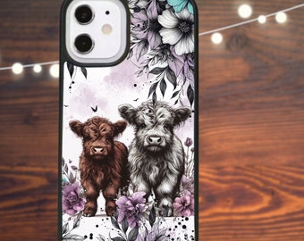 May include: A phone case with a white background and a design of two Highland cows standing in a field of purple flowers. The cows are brown and white and have black noses. The flowers are stylized and have a watercolor effect.