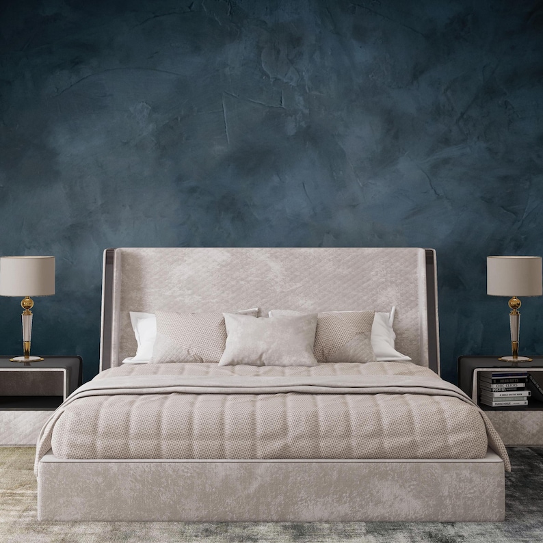 May include: A beige upholstered bed frame with a tall headboard and a textured quilt, flanked by two matching nightstands. Each nightstand features a lamp with a cylindrical shade and a clear, faceted base. The bed is dressed in neutral bedding.