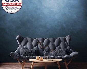 Könnte beinhalten: Ein dunkelgraues, gestepptes Sofa mit hoher Rückenlehne und ausgestellten Armlehnen sowie zwei passenden strukturierten Kissen. Ein Couchtisch aus hellem Holz steht davor, darauf eine Glasvase mit Zweigen und zwei beigefarbene Kerzen.