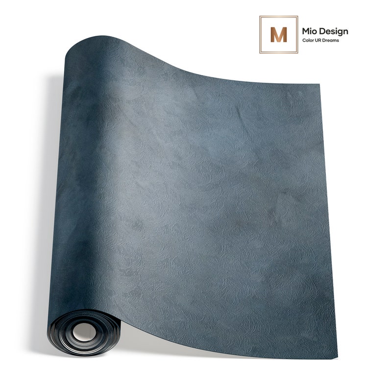May include: A roll of dark blue wallpaper featuring a textured, mottled surface pattern. The top right corner displays a logo with the letter M inside a square and the text Mio Design Color UR Dreams. The wallpaper has a matte finish.