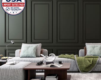 May include: A living room scene featuring a low-profile gray sectional sofa with light green throw pillows and a chunky knit olive green blanket. A dark wood coffee table holds an open book, two black cups, and a white abstract sculpture.