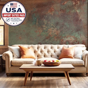May include: A tufted cream-colored sofa with two orange throw pillows and two white throw pillows, positioned in front of a wall with a weathered, oxidized copper-green and brown texture. A wooden coffee table holds a bowl of assorted fruit.