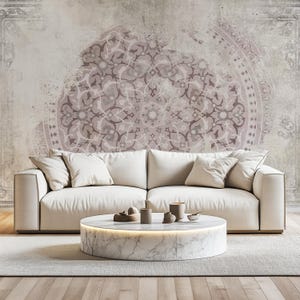 Peut inclure: Un canapé blanc avec deux coussins est placé devant un mur avec un grand motif de mandala rose et gris délavé. Une table basse en marbre blanc avec un piétement en bois clair se trouve devant le canapé.