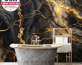 May include: A freestanding gray bathtub with a gold-toned rim and faucet, positioned in front of a wall featuring a black and white marble pattern with prominent gold veining. A gold-toned metal towel rack holds white towels next to the bathtub.