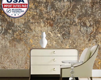 May include: A white three-drawer chest sits against a wall with brown and gold damask wallpaper. A white vase rests on the chest, and a white upholstered chair with a glass side table is positioned in front of the chest.