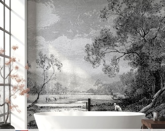 May include: A wall mural featuring a black and white landscape illustration with a large tree in the foreground, a field with figures, and a cloudy sky. The scene is printed on a wall behind a white, oval-shaped, freestanding bathtub.