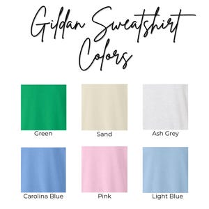 K&ouml;nnte beinhalten: Farbtabelle f&uuml;r Gildan-Sweatshirts. Sechs Farbfelder sind abgebildet: Gr&uuml;n, Sand, Aschgrau, Carolina-Blau, Rosa und Hellblau. Der Text "Gildan Sweatshirt Colors" ist in Schreibschrift oben im Bild zu sehen.