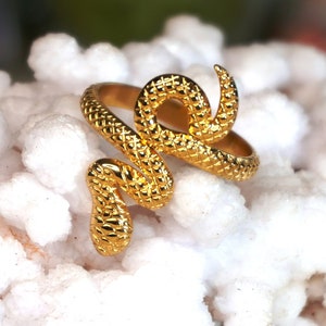 May include: A gold-toned snake ring with a textured surface. The ring is designed to wrap around the finger.