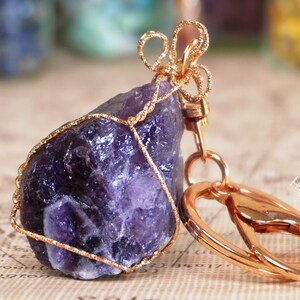 Peut inclure: Un cristal d'améthyste violet enveloppé de fil d'or avec un porte-clés en métal doré.