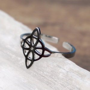 May include: A silver adjustable ring with a Celtic knot design. The ring is made of stainless steel and has a delicate, intricate pattern.