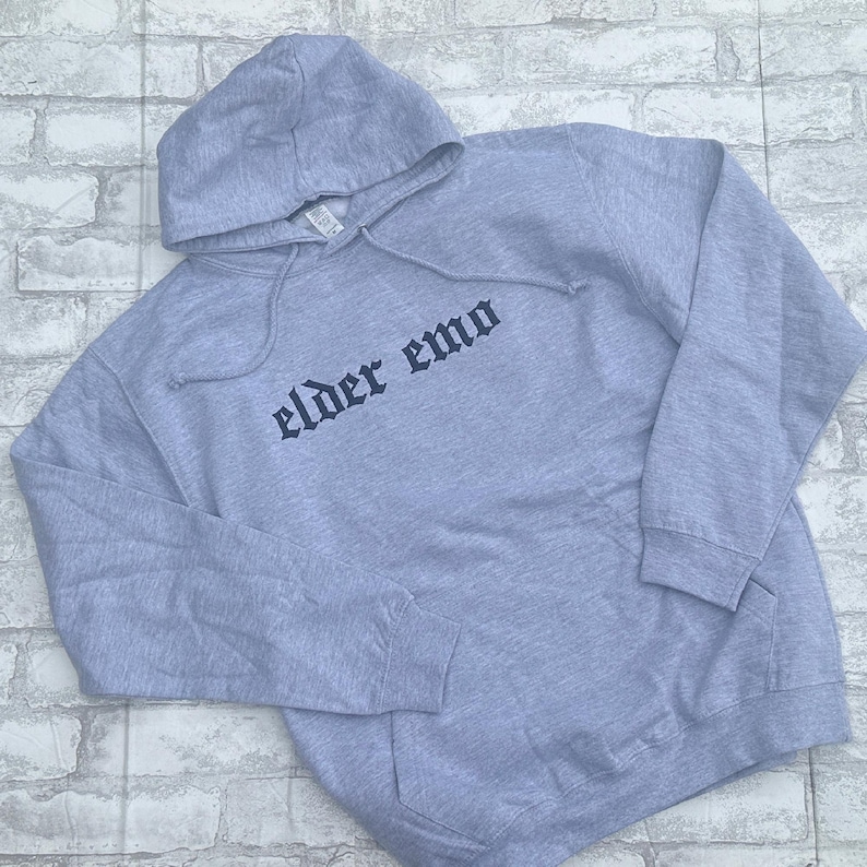 May include: A gray hooded sweatshirt with the text "elder emo" printed in black on the front.