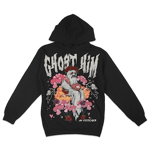 May include: Black hooded sweatshirt featuring a graphic print of a ghost holding a heart-shaped box. The text "Ghost Him" is printed in a gothic font above the ghost. The text "In Stitches" is printed below the ghost.