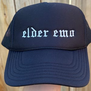 May include: Black trucker hat with a white embroidered design that says "elder emo".