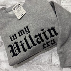 May include: Gray sweatshirt with black embroidered text that reads "in my Villain era".