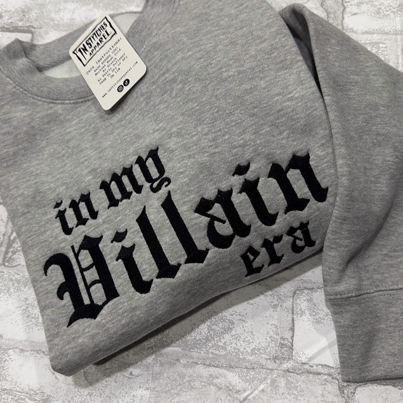 May include: Gray sweatshirt with black embroidered text that reads "in my Villain era".