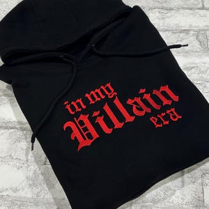 May include: Black hooded sweatshirt with red embroidered text that reads "in my Villain era".