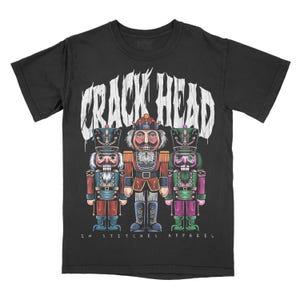 May include: Black t-shirt featuring a white graphic of three nutcracker soldiers. The text "Crack Head" is above the soldiers and "In Stitches Apparel" is below them.