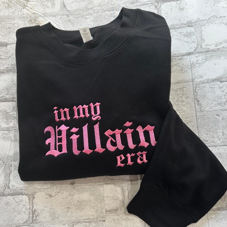 May include: Black sweatshirt with pink embroidered text that reads "in my Villain era".