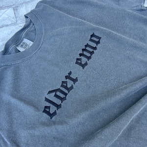 Puede incluir: Camiseta gris de manga larga con texto bordado en negro que dice "Elder Emo".