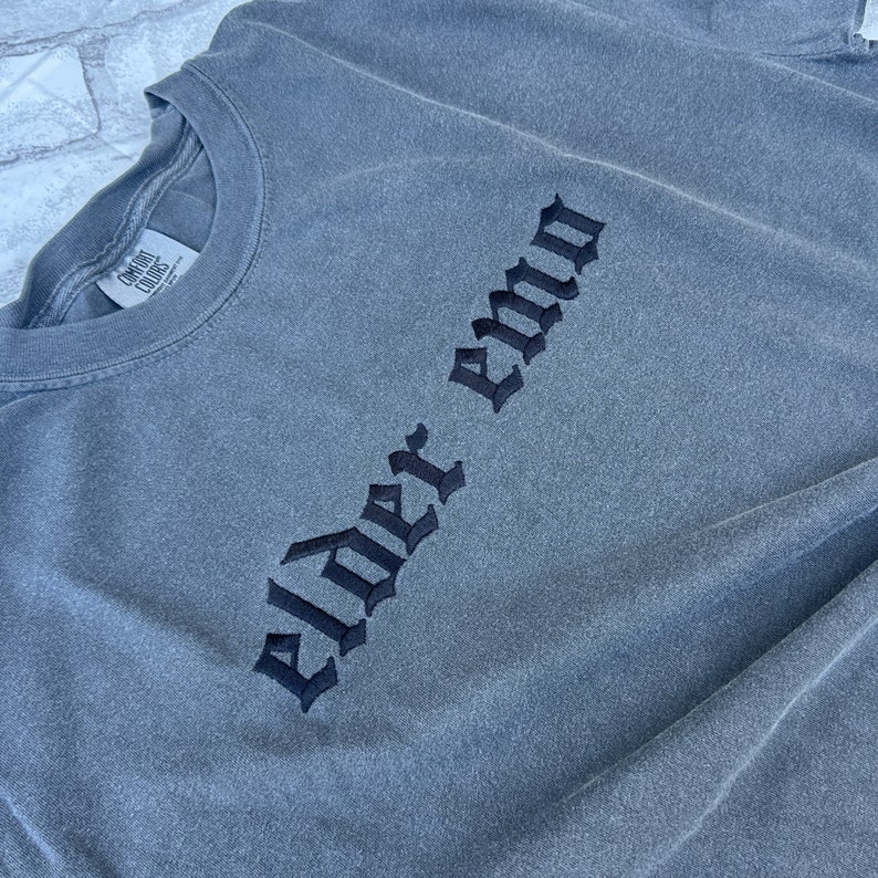 Puede incluir: Camiseta gris de manga larga con texto bordado en negro que dice "Elder Emo".