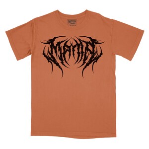 Może przedstawiać: Pomarańczowy t-shirt z czarnym nadrukiem słowa "MAYHEM" w stylizowanym, gotyckim kroju pisma.