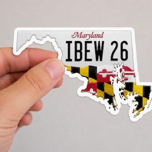 May include: A white sticker in the shape of the state of Maryland, featuring a license plate design. The plate reads "Maryland" in script above "IBEW 26" in bold black letters. The state outline is filled with a black, yellow, and red pattern.