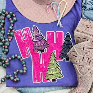 May include: A purple t-shirt with the words "HO HO HO" in hot pink, featuring sequined Christmas trees. The image includes a pink hat, candy canes, a beaded necklace, a purse, and a pair of pink cowboy boots.