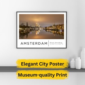 Puede incluir: Un póster con una vista nocturna de Ámsterdam, Países Bajos. El póster tiene un marco negro y un fondo blanco con el texto "AMSTERDAM" y "Nieuwe Amstelbrug 52.3562° N, 4.9061° E" en texto negro. El póster presenta una ciudad con un río y edificios iluminados por la noche.