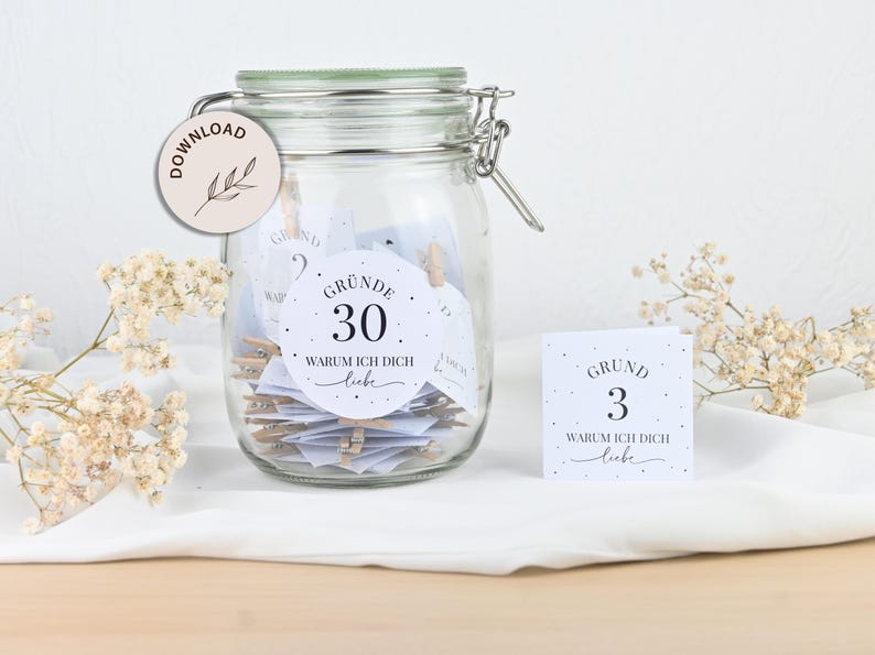 May include: A glass jar filled with white cards with black text. The cards have the text "Gr&uuml;nde 30 Warum ich dich liebe" and "Grund 3 Warum ich dich liebe".