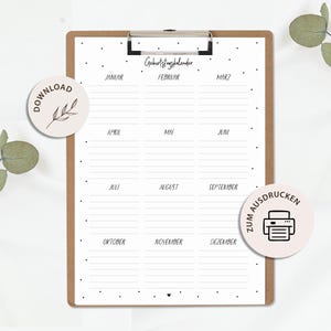 May include: A white paper birthday calendar with black text and a polka dot border, held on a brown wooden clipboard. The calendar features twelve months labelled in German, with lined sections for each month and a small heart icon at the bottom.