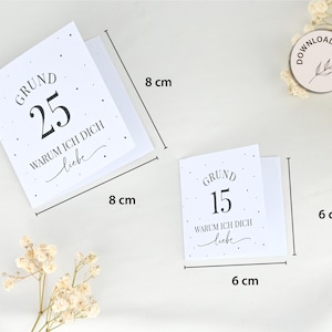 May include: Two white cards with black text and small black dots. The larger card reads "GRUND 25 WARUM ICH DICH liebe" and measures 8 inches by 8 inches. The smaller card reads "GRUND 15 WARUM ICH DICH liebe" and measures 6 inches by 6 inches.