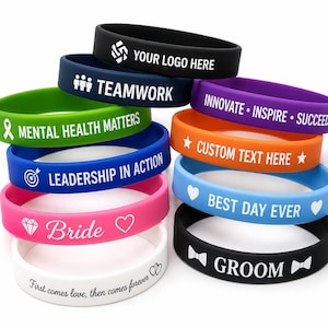 May include: A stack of colorful silicone wristbands with white text. The bands are in various colors, including black, blue, green, pink, orange, purple, and white. Text includes "YOUR LOGO HERE", "TEAMWORK", "MENTAL HEALTH MATTERS", "LEADERSHIP IN ACTION", "Bride", "First comes love, then comes forever", "INNOVATE • INSPIRE • SUCCEED", "CUSTOM TEXT HERE", "BEST DAY EVER", and "GROOM".