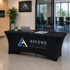 Könnte beinhalten: Schwarze Tischdecke mit dem Ascend Solutions Logo in Weiß und Blau. Ein Laptop, Stifte und eine kleine Pflanze befinden sich auf dem Tisch. Der Text "Ascend Solutions Elevate Your Business" ist zu sehen. Der Hintergrund zeigt eine Büroumgebung.
