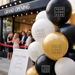 May include: A cluster of black, white, and gold balloons, each featuring a square graphic with the text 'YOUR LOGO HERE'. The balloons are positioned in front of a storefront with a sign reading 'GRAND OPENING' and a welcome sign.