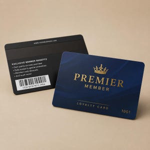 Peut inclure: Deux cartes de fidélité. L'une est noire avec du texte blanc, comprenant un code-barres et l'adresse du site Web. L'autre est bleu marine avec du texte doré qui se lit "Premier Member" et "Loyalty Card". Une couronne dorée est au-dessus du mot "Premier".