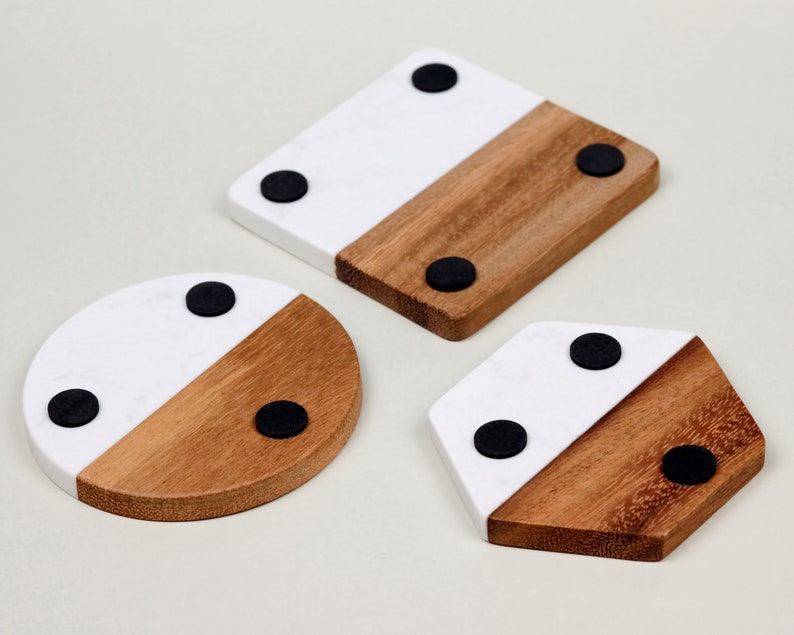 May include: Three round, square, and hexagonal coasters made of wood and white marble with black rubber feet on the bottom.