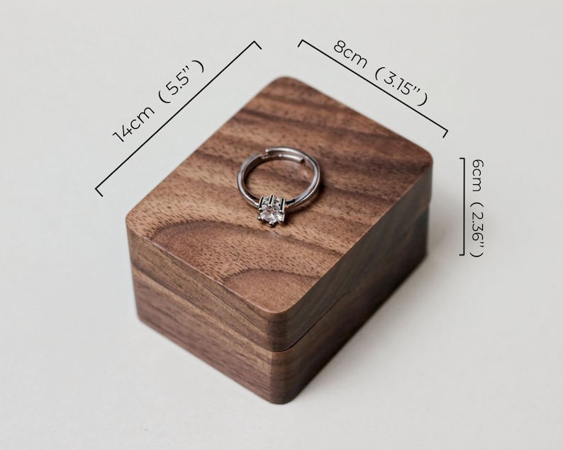 May include: A wooden ring box made of walnut wood with a ring inside. The box measures 5.5 inches long, 3.15 inches wide, and 2.36 inches high.
