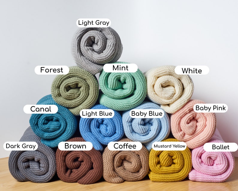 May include: A collection of 12 rolled up knitted blankets in various colors, including light gray, forest green, mint green, white, canal blue, baby pink, light blue, baby blue, dark gray, brown, coffee brown, mustard yellow, and ballet pink.