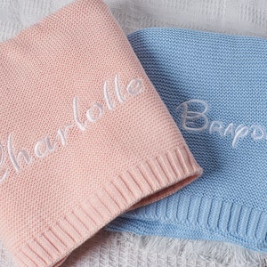 May include: Two knitted baby blankets, one pink with the name "Charlotte" embroidered on it and one blue with the name "Braden" embroidered on it.