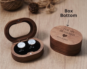 May include: A wooden box with a hinged lid, open to reveal two cufflinks. The box is engraved with "FOR MY HUSBAND" and a heart, with the date "JULY 28, 2025". The cufflinks have a white background with black text. The box is oval-shaped.