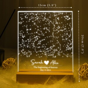 Puede incluir: Una luz nocturna de acr&iacute;lico blanco con un dise&ntilde;o de constelaci&oacute;n y los nombres "Sarah" y "Alix" con un s&iacute;mbolo de coraz&oacute;n. El texto debajo dice "The beginning of forever" y "May 15 2014". La luz nocturna mide 15 cm de ancho y 20 cm de alto.