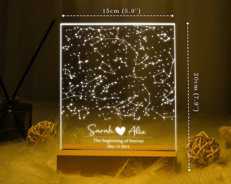 Puede incluir: Una luz nocturna de acr&iacute;lico blanco con un dise&ntilde;o de constelaci&oacute;n y los nombres "Sarah" y "Alix" con un s&iacute;mbolo de coraz&oacute;n. El texto debajo dice "The beginning of forever" y "May 15 2014". La luz nocturna mide 15 cm de ancho y 20 cm de alto.