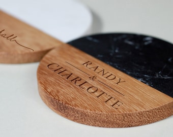 May include: Two round wooden coasters with a black and white marble design. One coaster has the text "Randy & Charlotte" engraved on it.