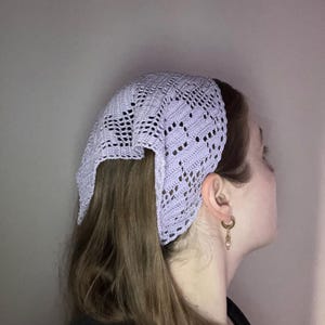 Puede incluir: Un pañuelo para la cabeza de ganchillo de color lila claro con un diseño geométrico calado. El cubrecabezas triangular está hecho de hilo suave. Este pañuelo está diseñado para ser usado en la cabeza, ofreciendo un accesorio delicado y elegante.